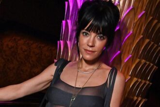 Η Lily Allen ποζάρει κρατώντας το άλμπουμ “West End Girl”, χαμογελώντας μετά την επιτυχία του